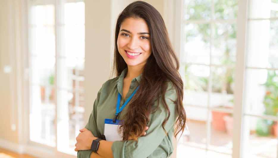 Young beautiful business woman wearing id card and smiling confident with crossed arms