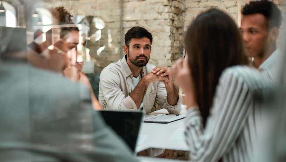 Brainstorming. Business people discussing something and working together while sitting at the office table behind the glass wall in the modern office. Meeting